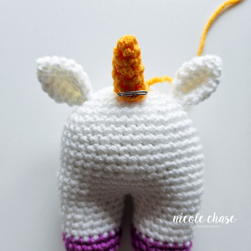 The horn has been pinned into place on top of the unicorn baby crochet pattern and is awaiting sewing.