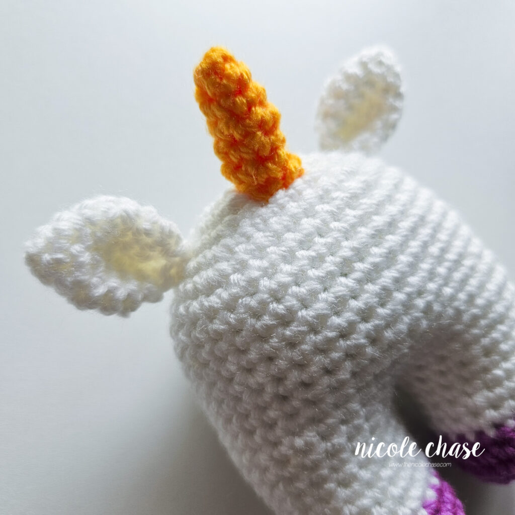 The unicorn horn has been sewn into place on the top of the crochet unicorn's head.