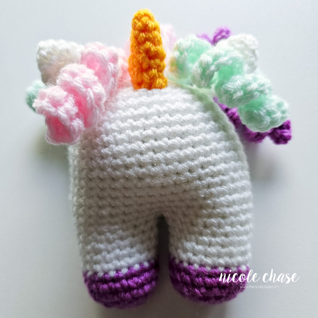 The face of the crochet unicorn prior to embroidering the sleepy eyes.