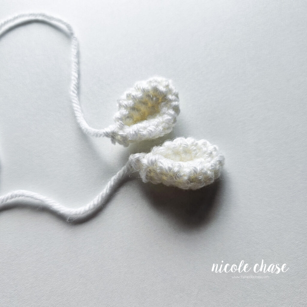 Two finished white ears for the unicorn baby toy crochet pattern, awaiting assembly.