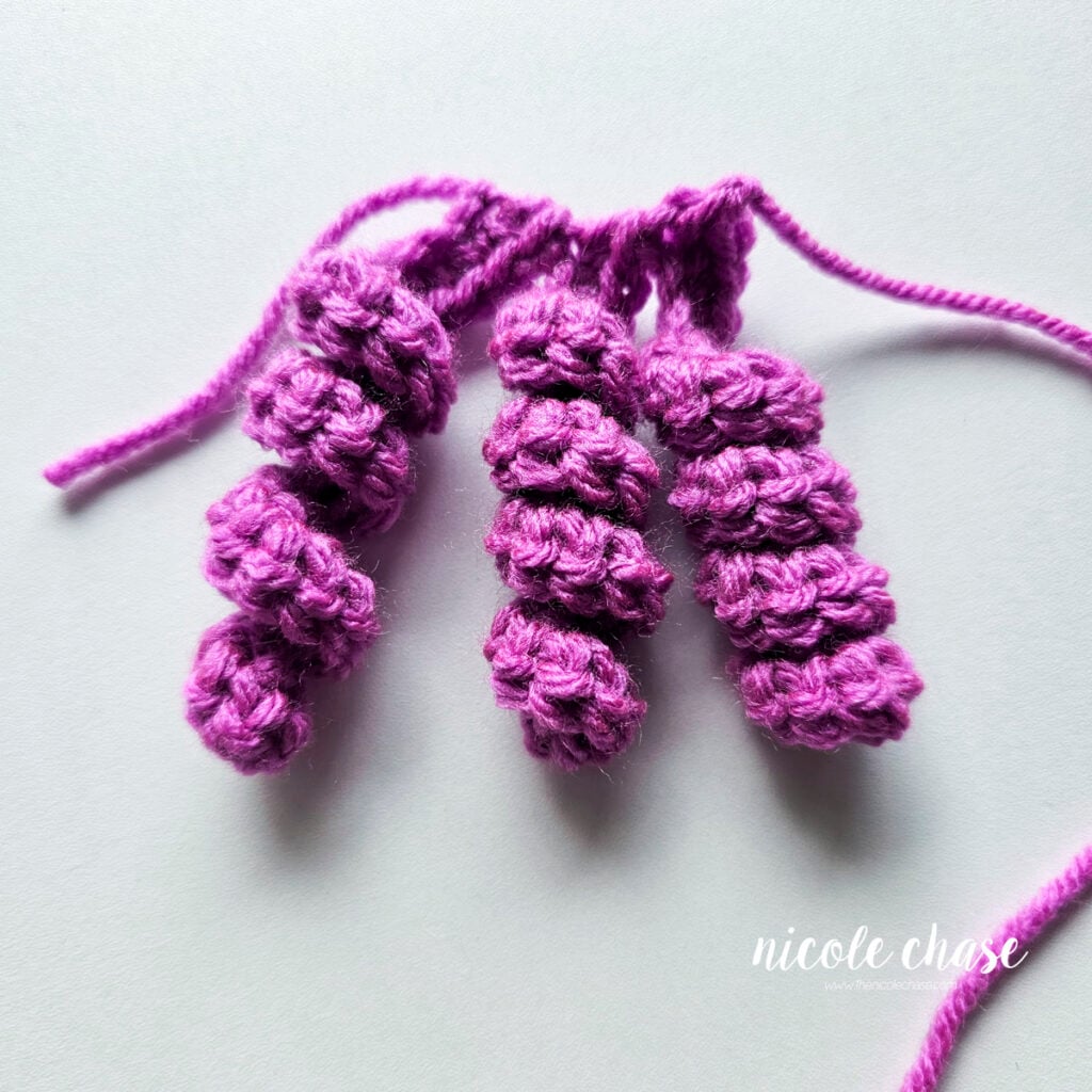 Hair Curl B has been completed in a purple yarn with a total of 3 curls attached.