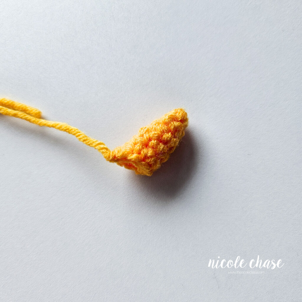 A finished bright orange horn for the crochet unicorn pattern, awaiting assembly.