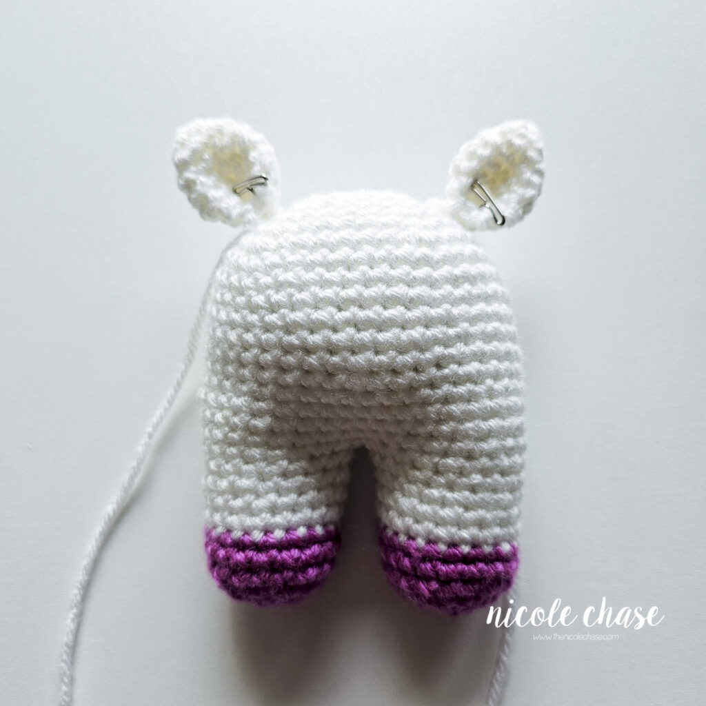 The crochet unicorn ears have been pinned into place on the top of the head and are awaiting sewing.