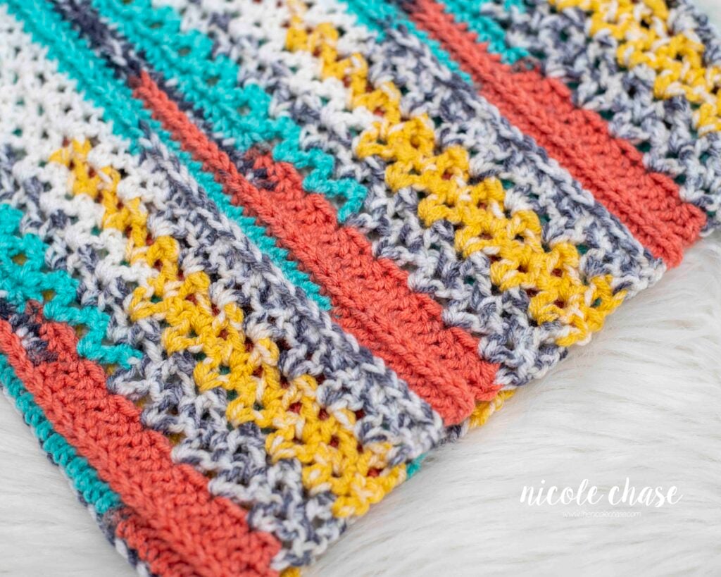 Close-up of the stitch texture of the New Beginnings Cowl free crochet cowl pattern, showing colorful stripes in teal, coral, yellow, and white.