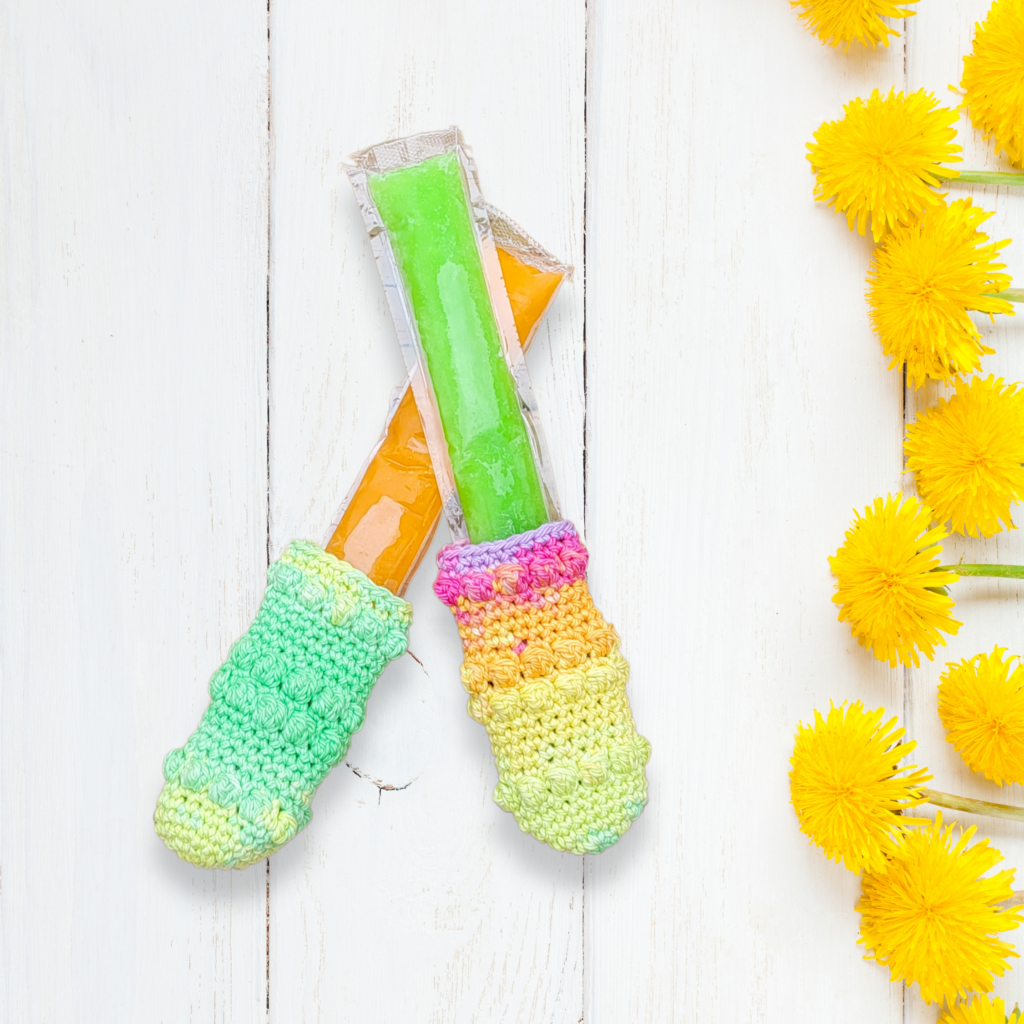 two colorful crochet freeze pop holders holding a frozen ice pop