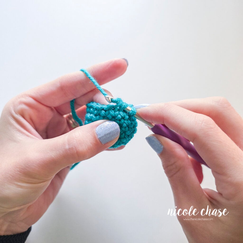 Starting to pull yarn through the two front loops on the crochet hook during an invisible decrease.