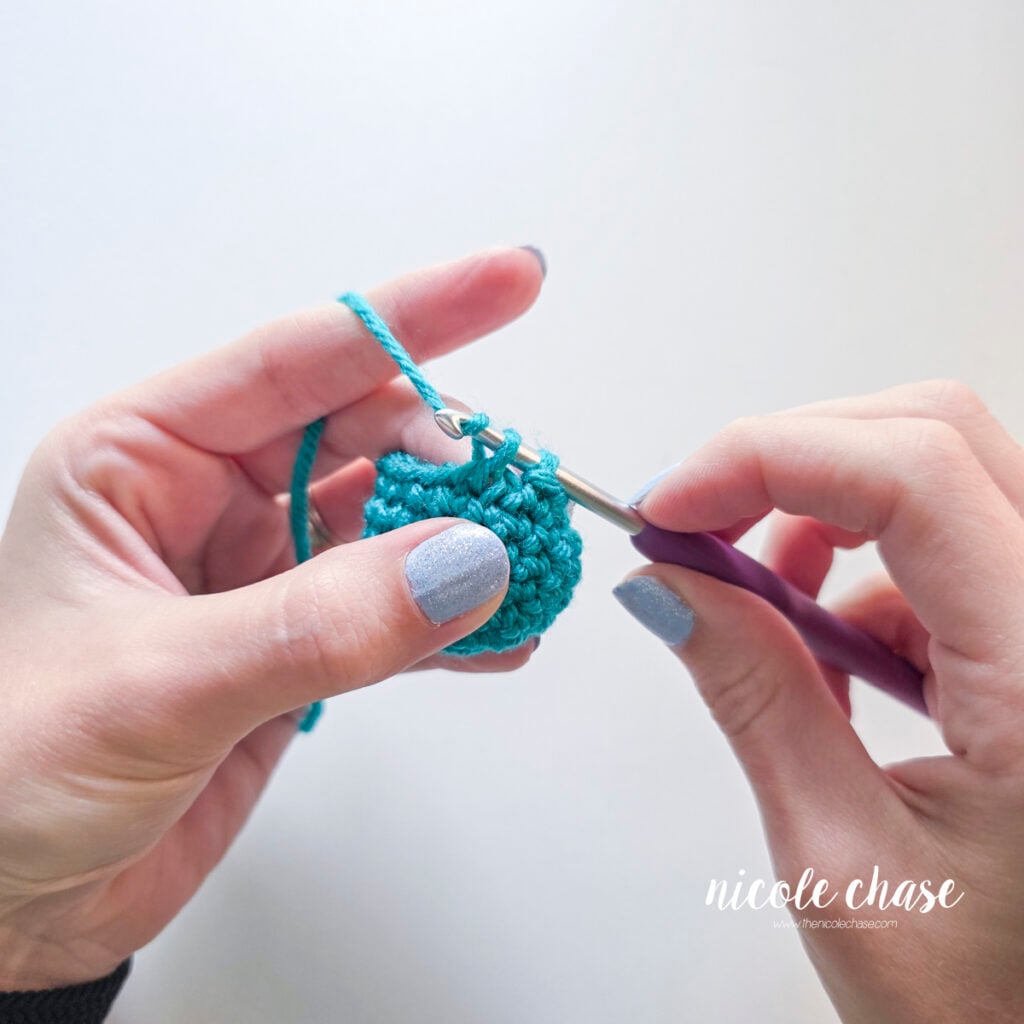 Pulling the yarn through the final two loops on the hook to complete the invisible decrease.