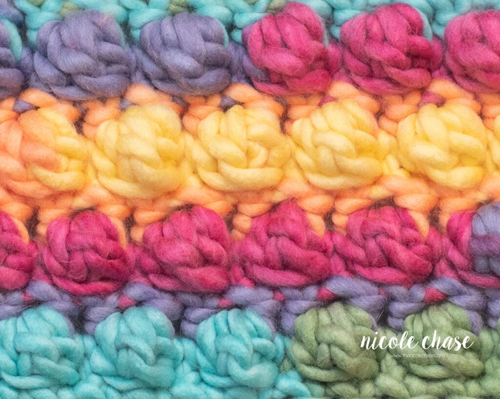 Close-up of a rainbow fabric showing the puffy texture of the crochet bobble stitch.