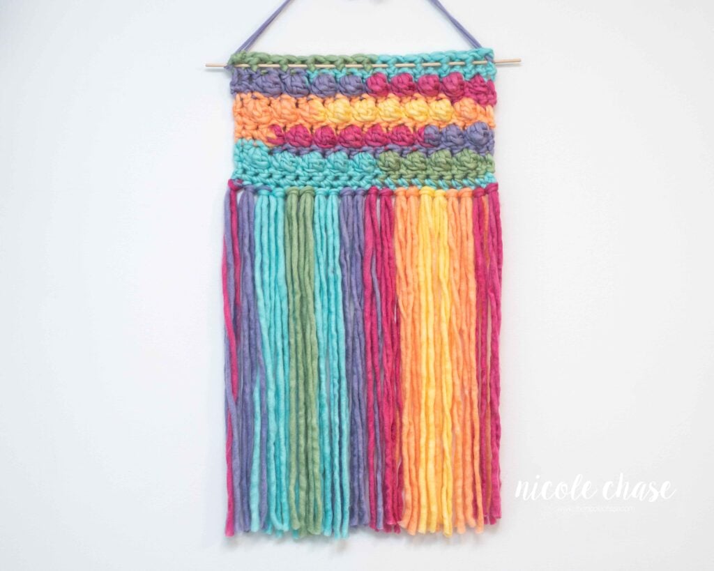 rainbow crochet wall hanging with long fringe and textured bobbles