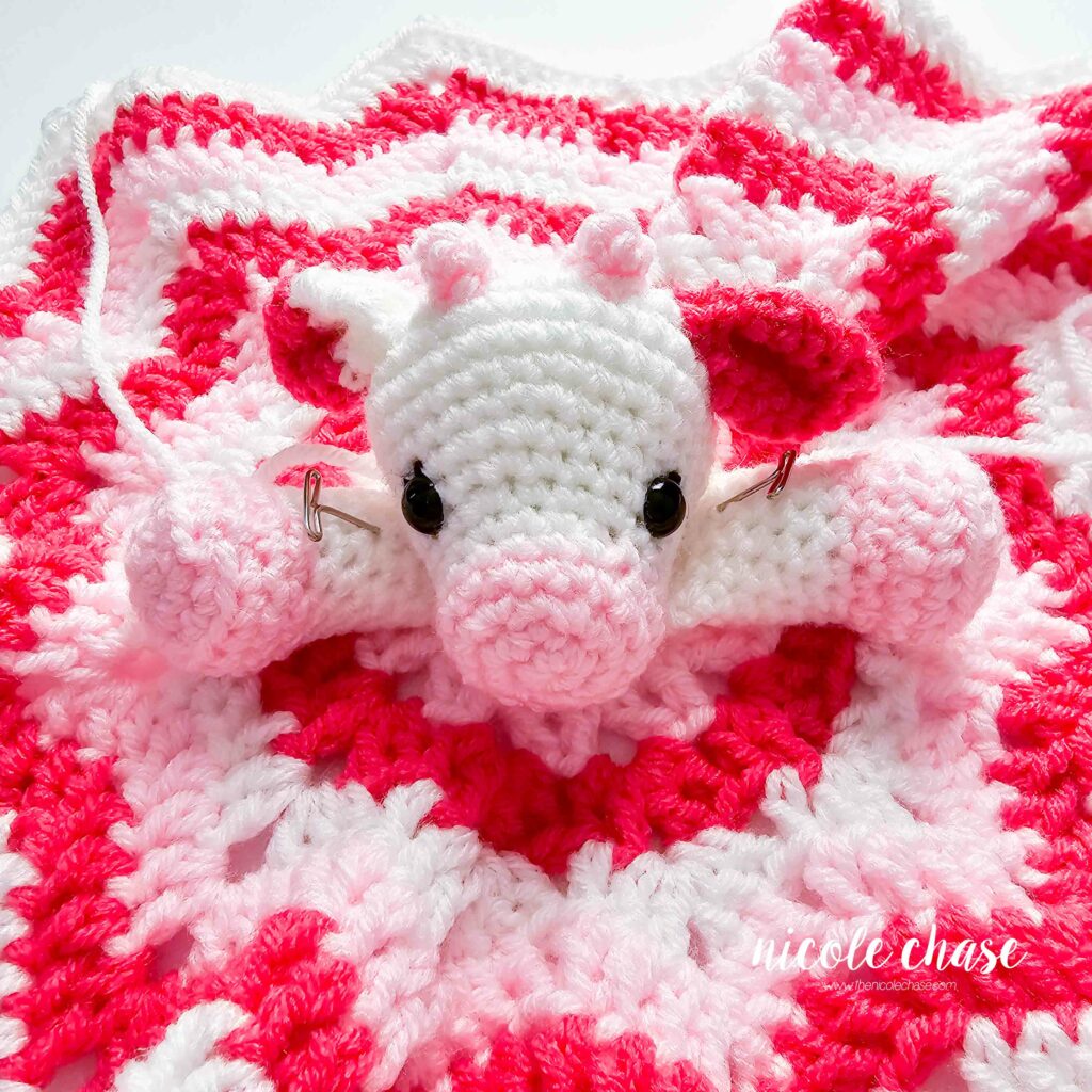 amigurumi cow head sewn to the blanket with arms pinned in place