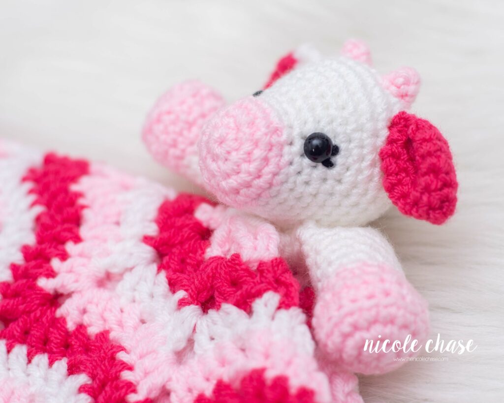 crochet cow lovey pattern made in light pink, dark pink, and white