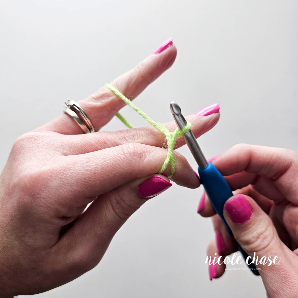 Loop has been created around the hook, while the yarn is still wrapped around the fingers, before the slip knot is formed.