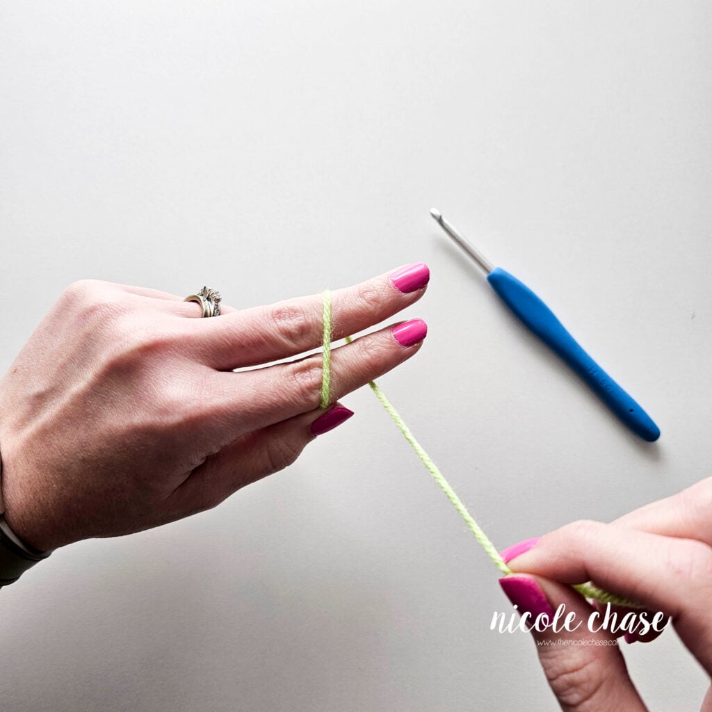 A tutorial image for the slip knot demonstrating the strand of yarn being wrapped around two fingers.