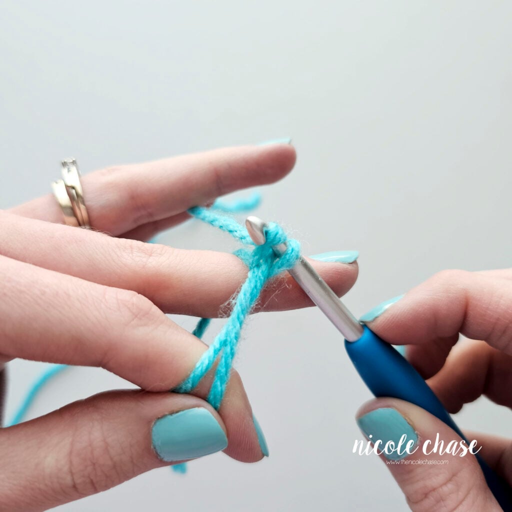 The hook is pulling up a loop with the working yarn to create a chain.