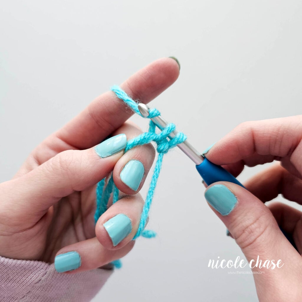 The working yarn is over the hook and being pulled down through the loops.