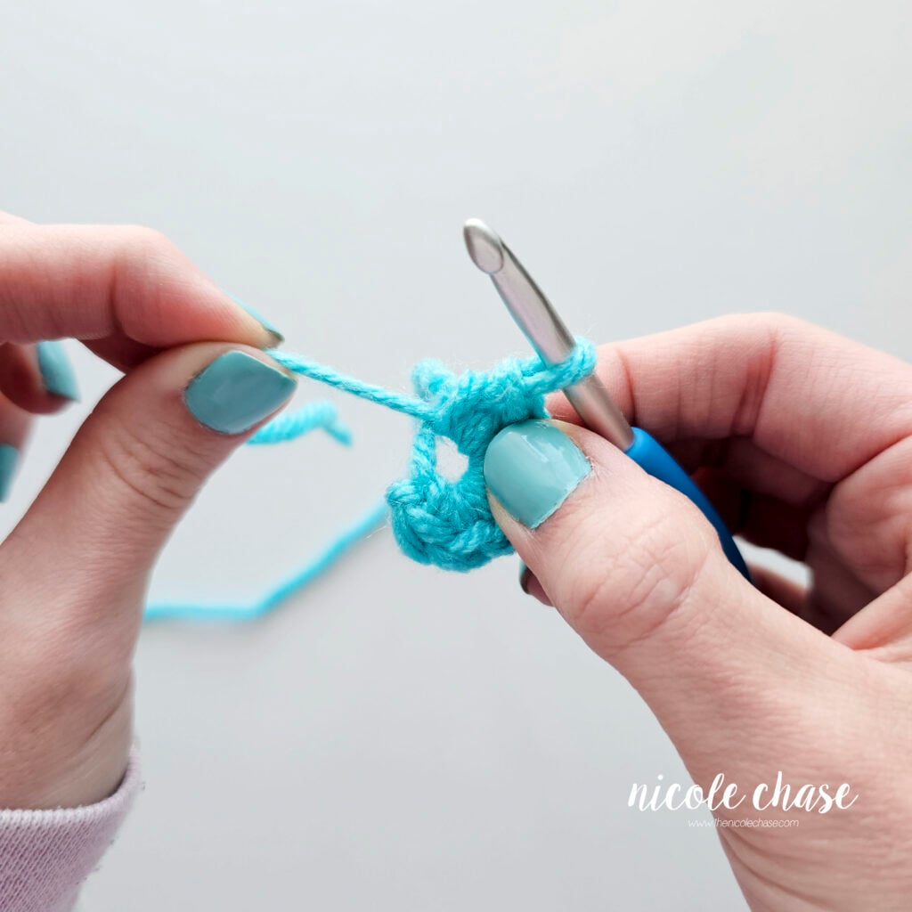 The hole in the center of the magic ring is getting smaller as the yarn tail is being pulled.