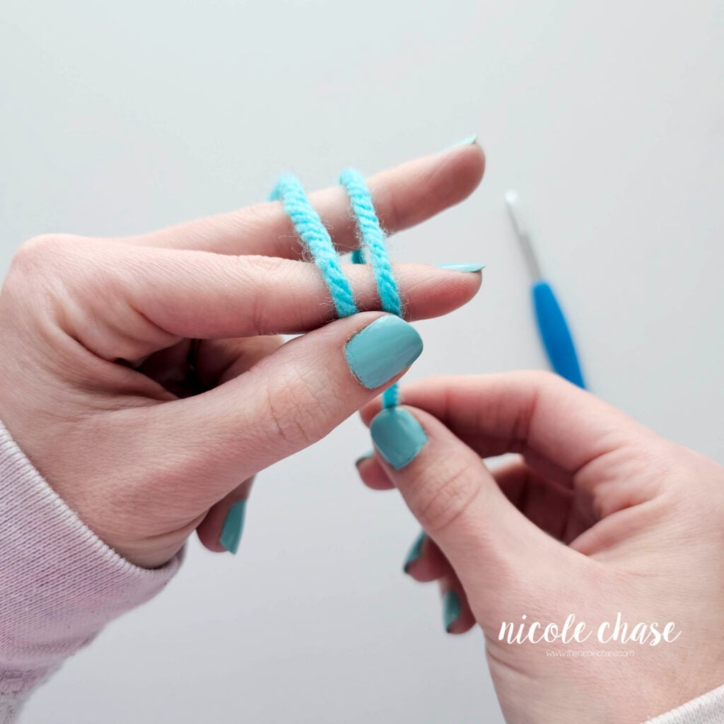 Photo showing the two loops of yarn being held with the thumb.