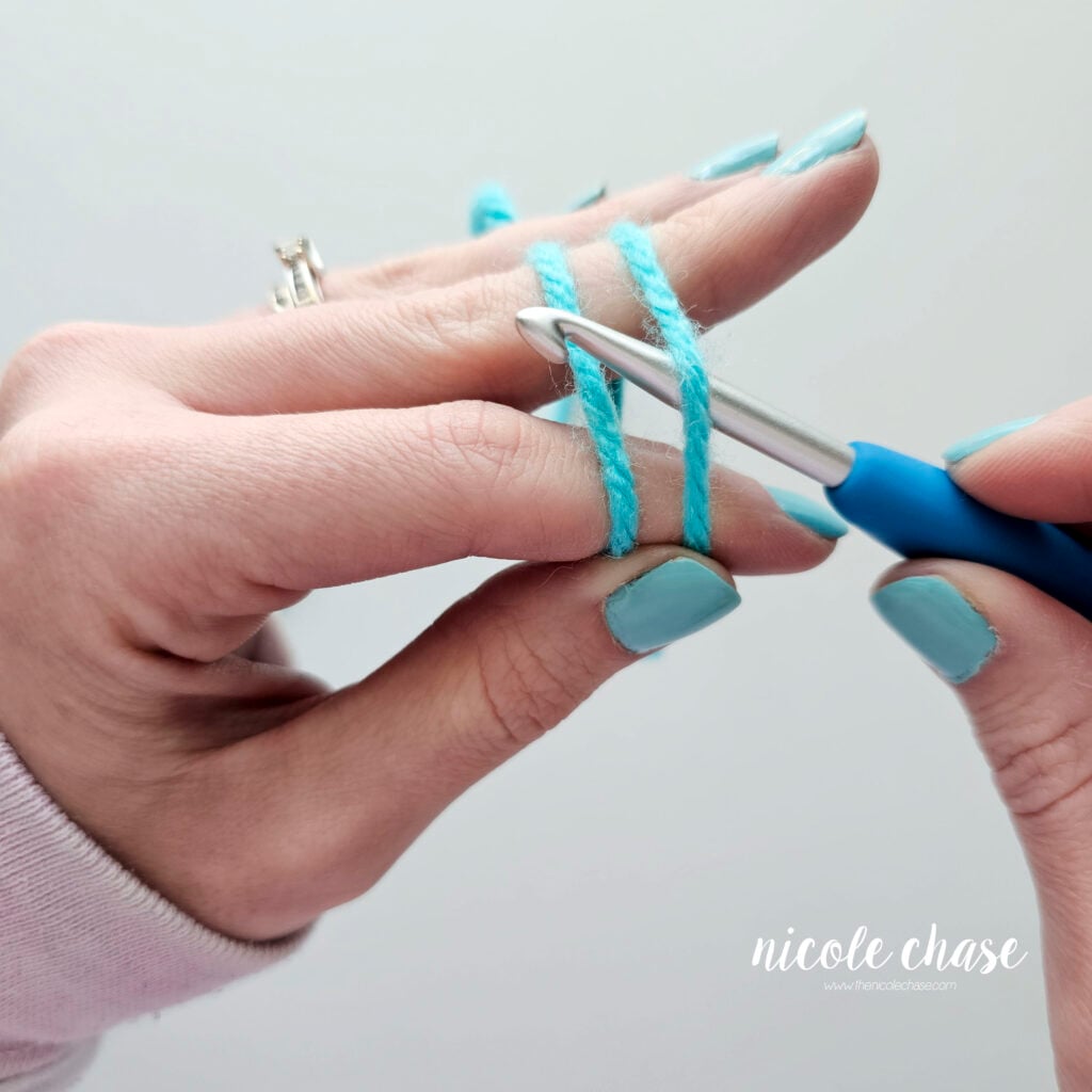 The crochet hook is under the first strand of yarn and over the back strand of yarn.