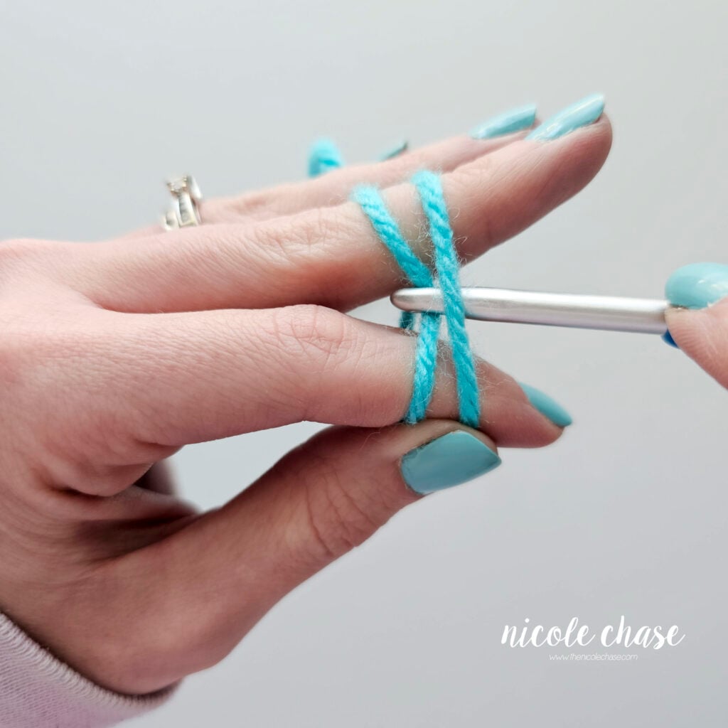 The crochet hook is pulling up the back strand of yarn.