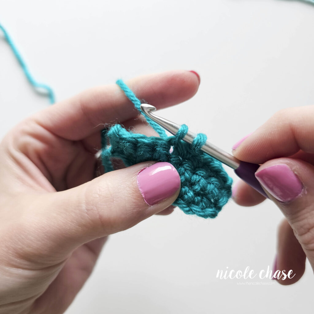 Demonstrating the process of working a single crochet stitch into another with two loops on the hook.