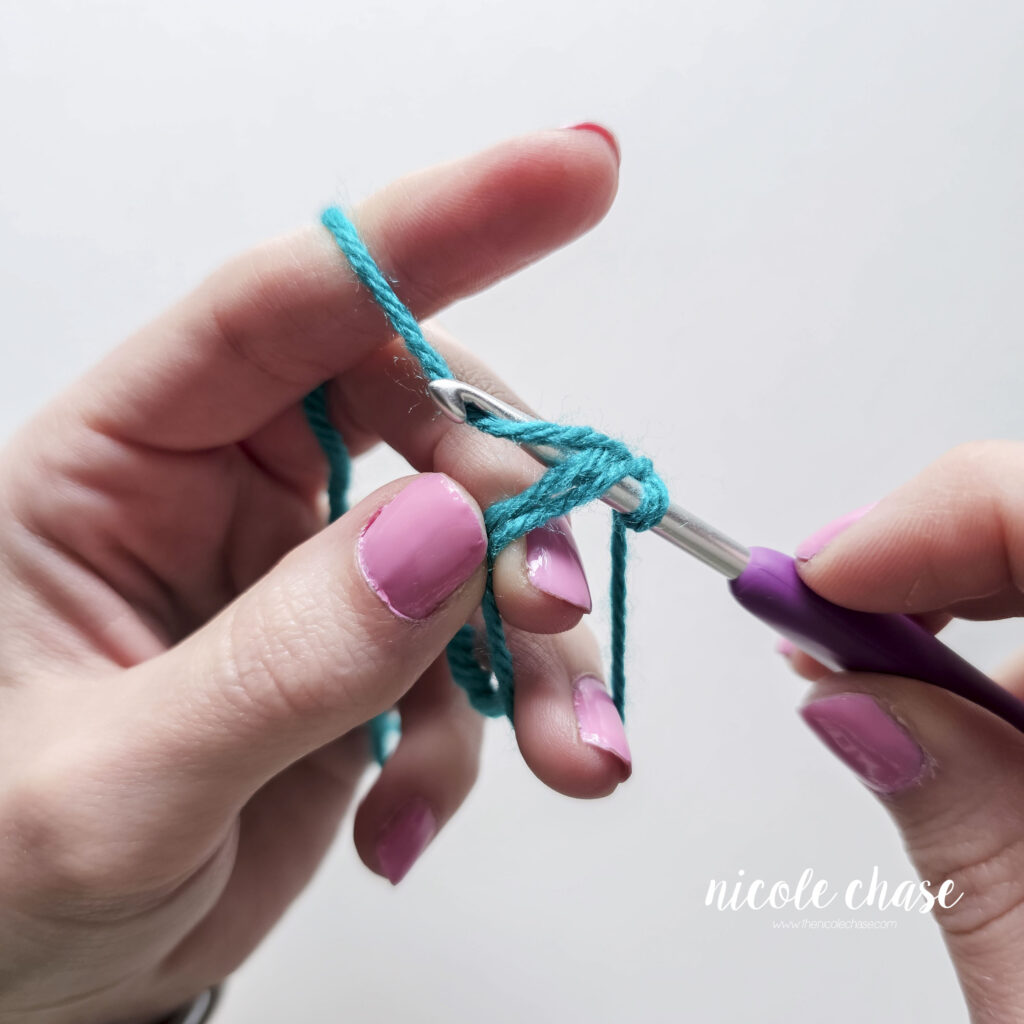 The hook has been inserted into the center of the magic ring and the yarn has been wrapped over the hook.