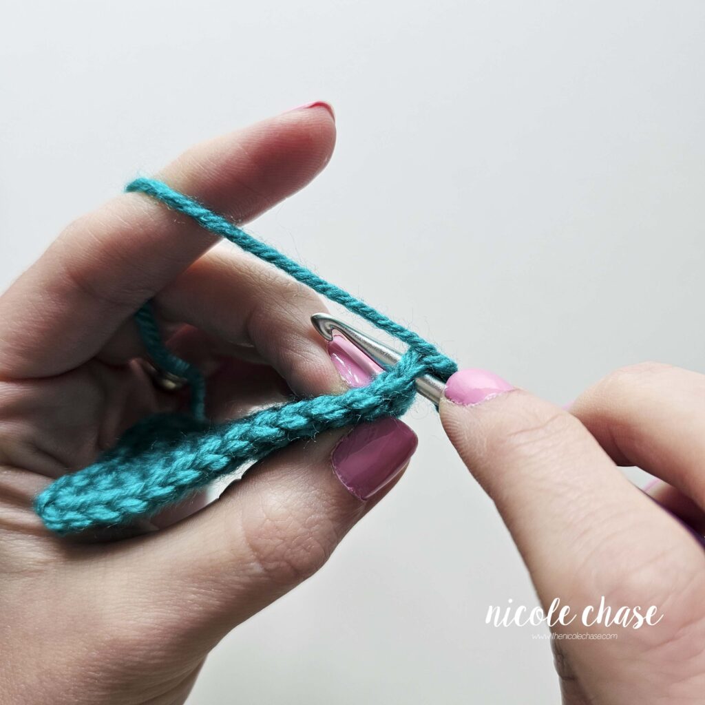 Tutorial image showing how to insert the hook into the first stitch when starting a single crochet decrease.