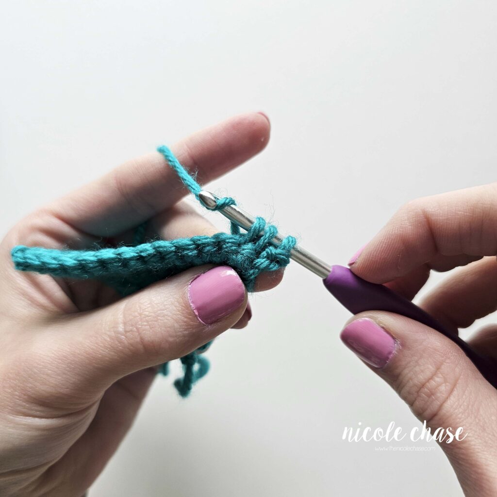 Step-by-step tutorial photo demonstrating a yarn over with three active loops remaining on the crochet hook during a standard decrease.