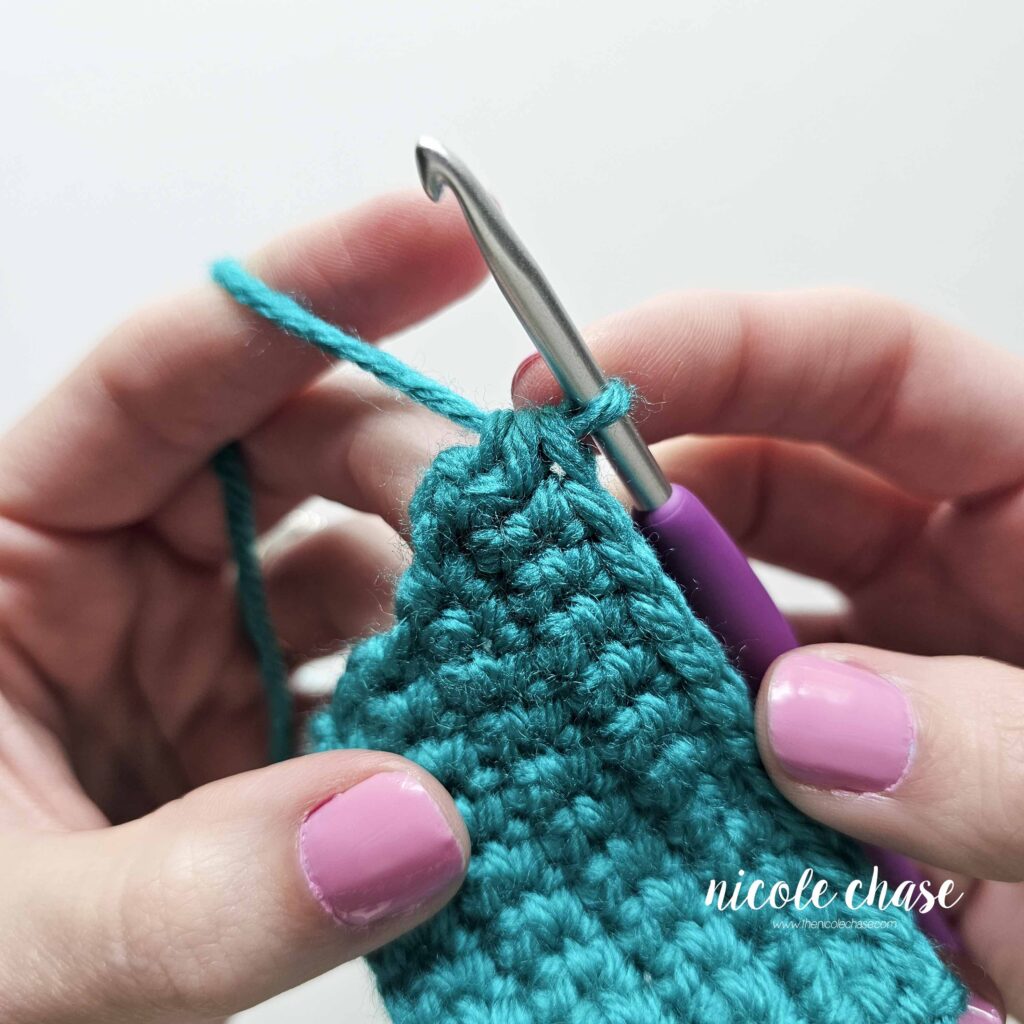 Tutorial image demonstrating the placement of a single crochet decrease stitch on the final edge of a row to narrow the fabric's width.