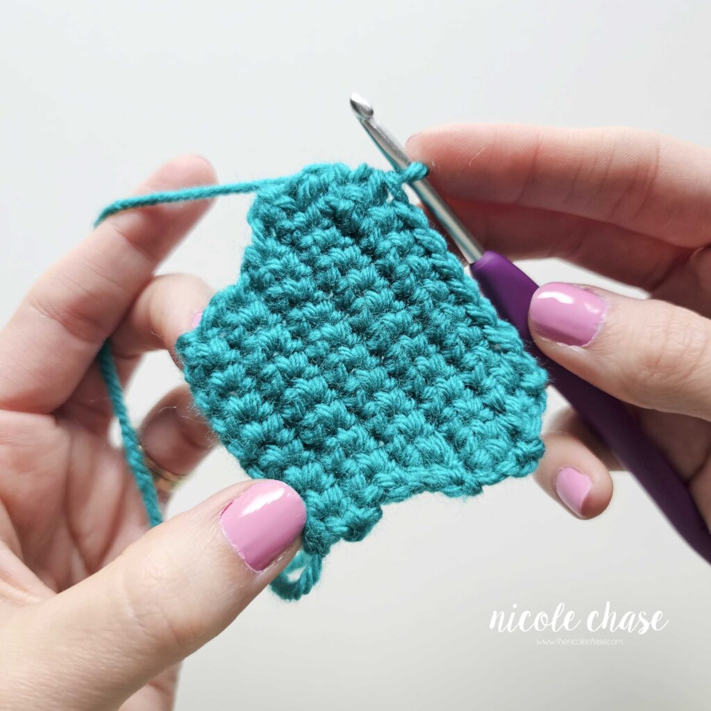 Progress photo of a teal single crochet swatch showing the physical result of consecutive decrease rows, illustrating how the fabric dramatically tapers inward.