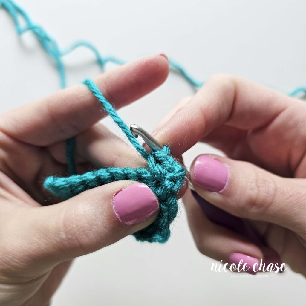Tutorial photo demonstrating step 2 of a single crochet increase. The image shows the completion of the second regular single crochet stitch in a teal yarn swatch.