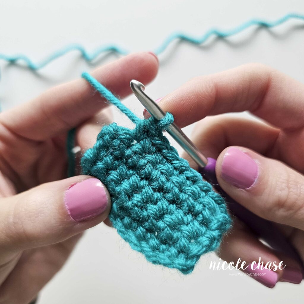 Tutorial image showing the mid-row progression of single crochet stitches in a teal yarn swatch before reaching the edge for shaping.