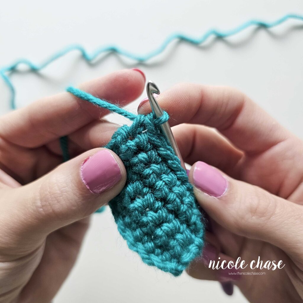 Step-by-step tutorial photo demonstrating the first single crochet placed into a stitch to begin an increase (inc) row.