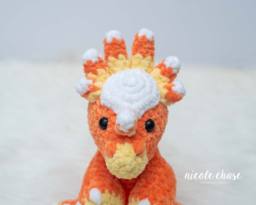 Close-up view of Mini Stevie the Stygimoloch's head showing white-tipped orange and yellow candy corn horns arranged along the top crown.