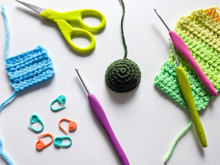 Crochet tools and practice swatches of basic stitches for crochet arranged on a white surface, including hooks, scissors, and stitch markers.