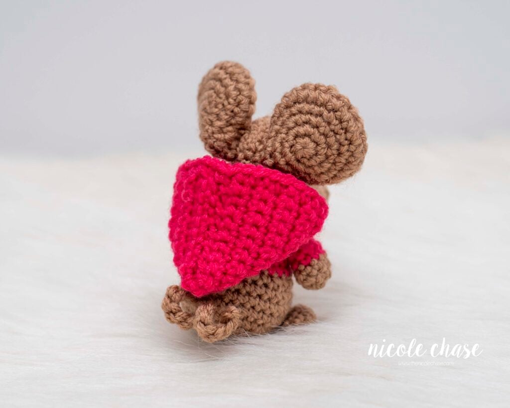 The back view of Mavis the Mouse showing the hood of the pink sweatshirt and the small curly tail. 