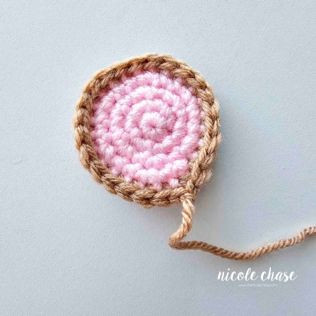 Shaping the mouse's crochet ear to create a pinched look, part 1.