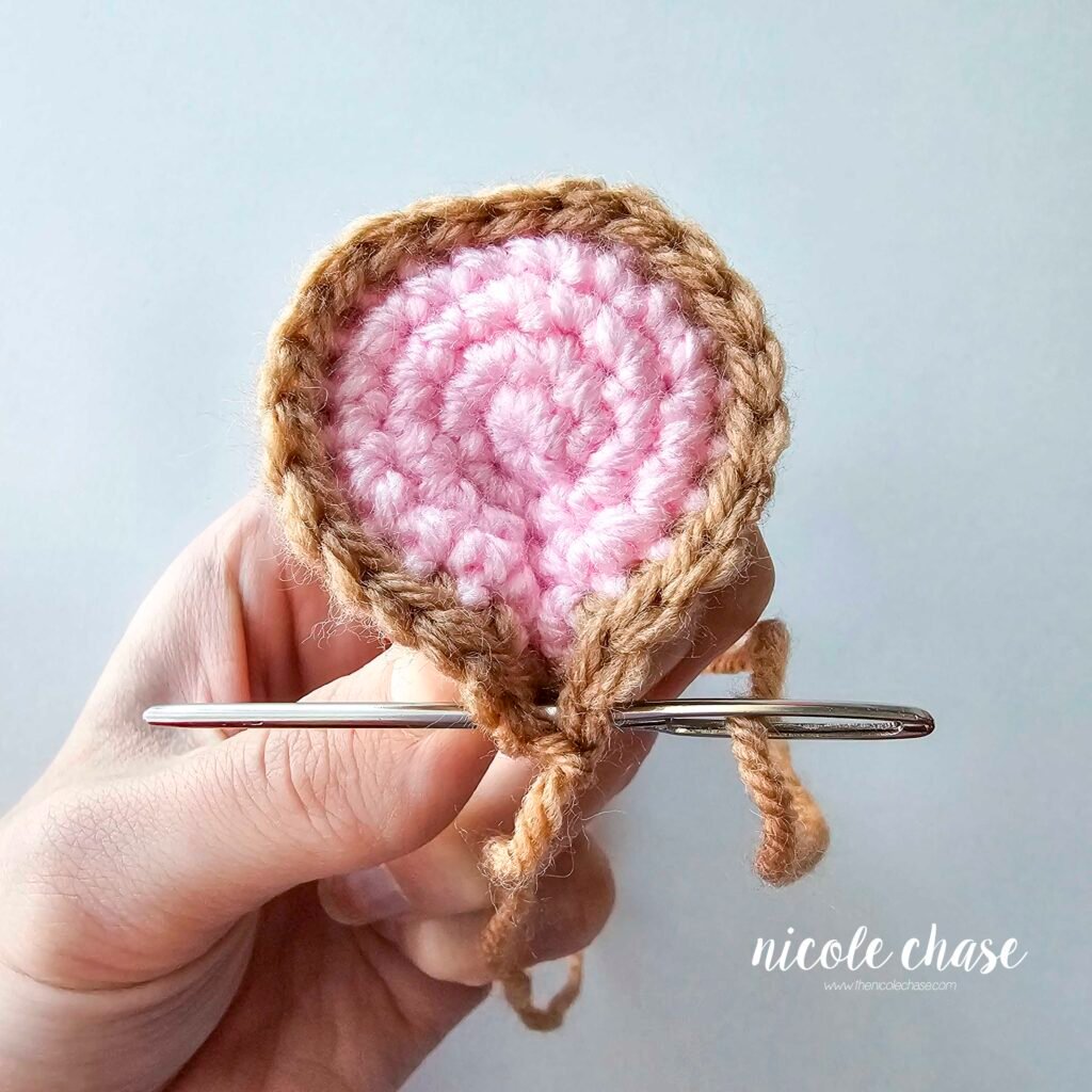 Shaping the mouse's crochet ear to create a pinched look, part 3.