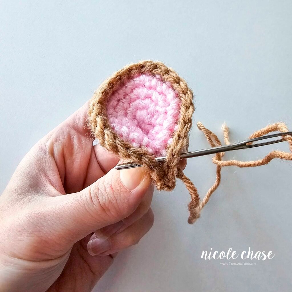 Shaping the mouse's crochet ear to create a pinched look, part 5.