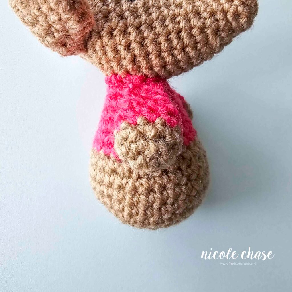 The arms of the crochet mouse have been sewn into place on each side of the body, view 1.