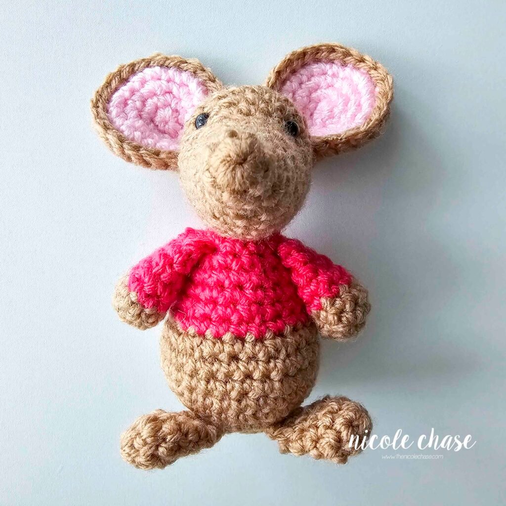The crochet mouse feet have been sewn into place on the bottom of the mouse body, view 1.