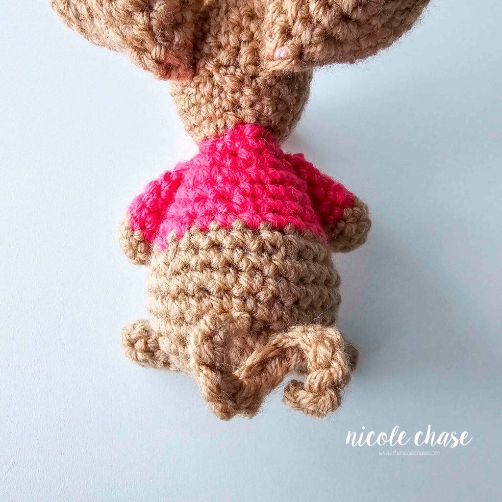 The mouse tail has been sewn into place on the back of the body, view 1. 