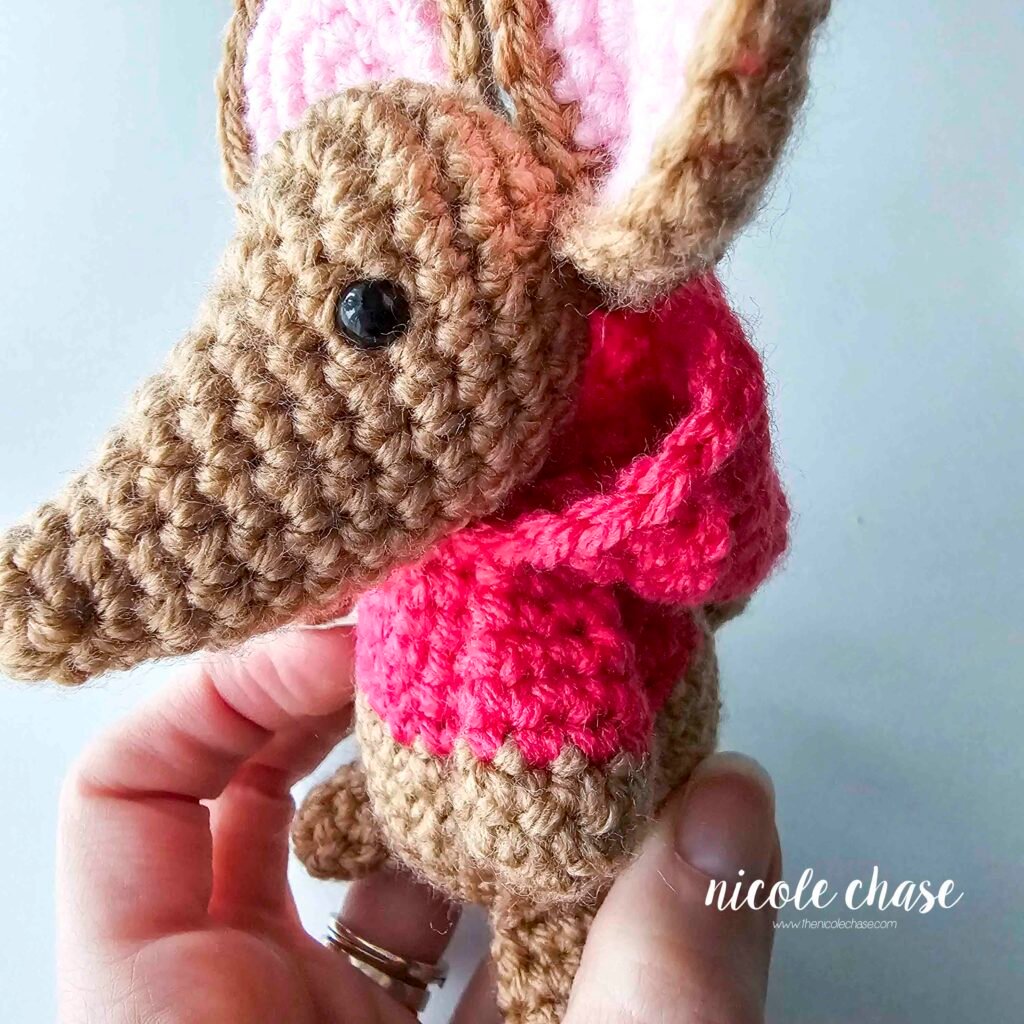 The hood of the crochet mouse's sweatshirt has been sewn into place behind the mouse's head, view 3.