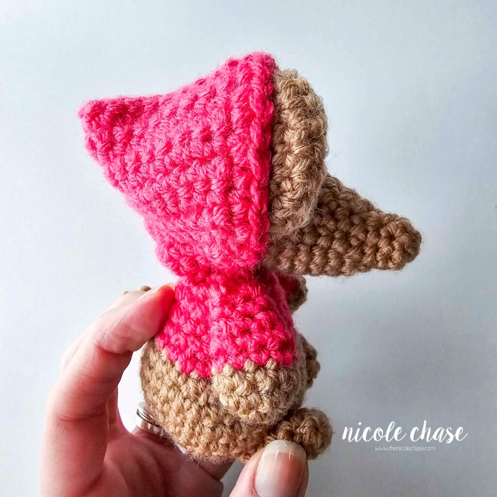 Demonstrating the hood being pulled over the crochet mouse's head and ears, view 2.