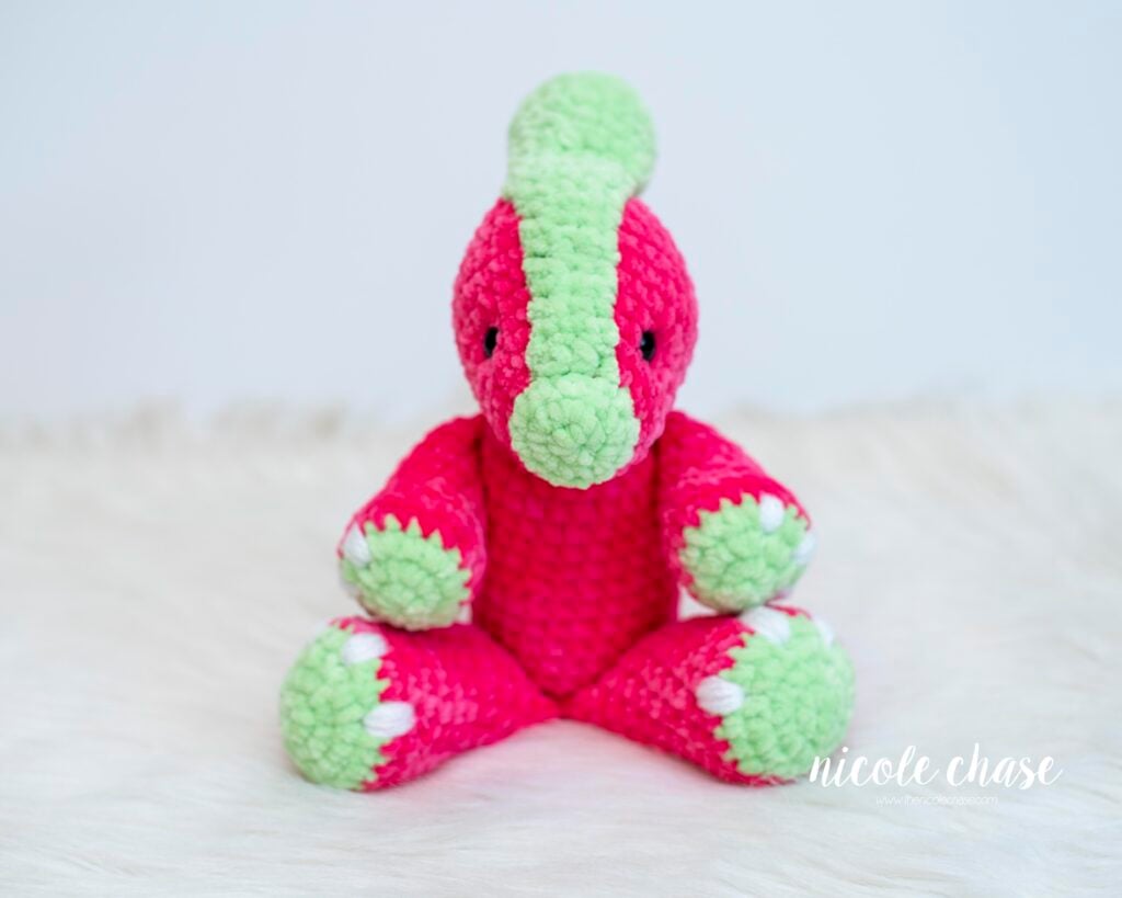 Mini Parker the Parasaurolophus chunky yarn amigurumi pattern finished project, showing a dark pink and green plush dinosaur.
