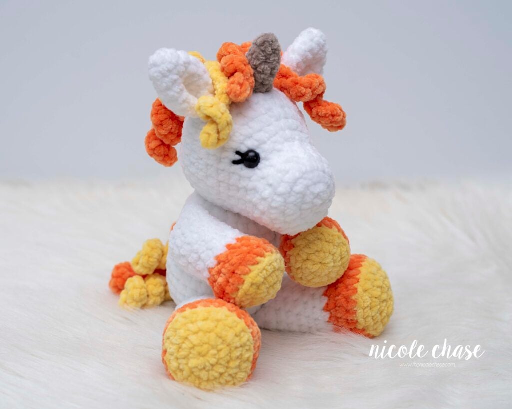 Mini Poppy the Unicorn crocheted in seasonal candy corn colors (orange, yellow, white). This customization demonstrates color changes for the free mini unicorn crochet pattern. 