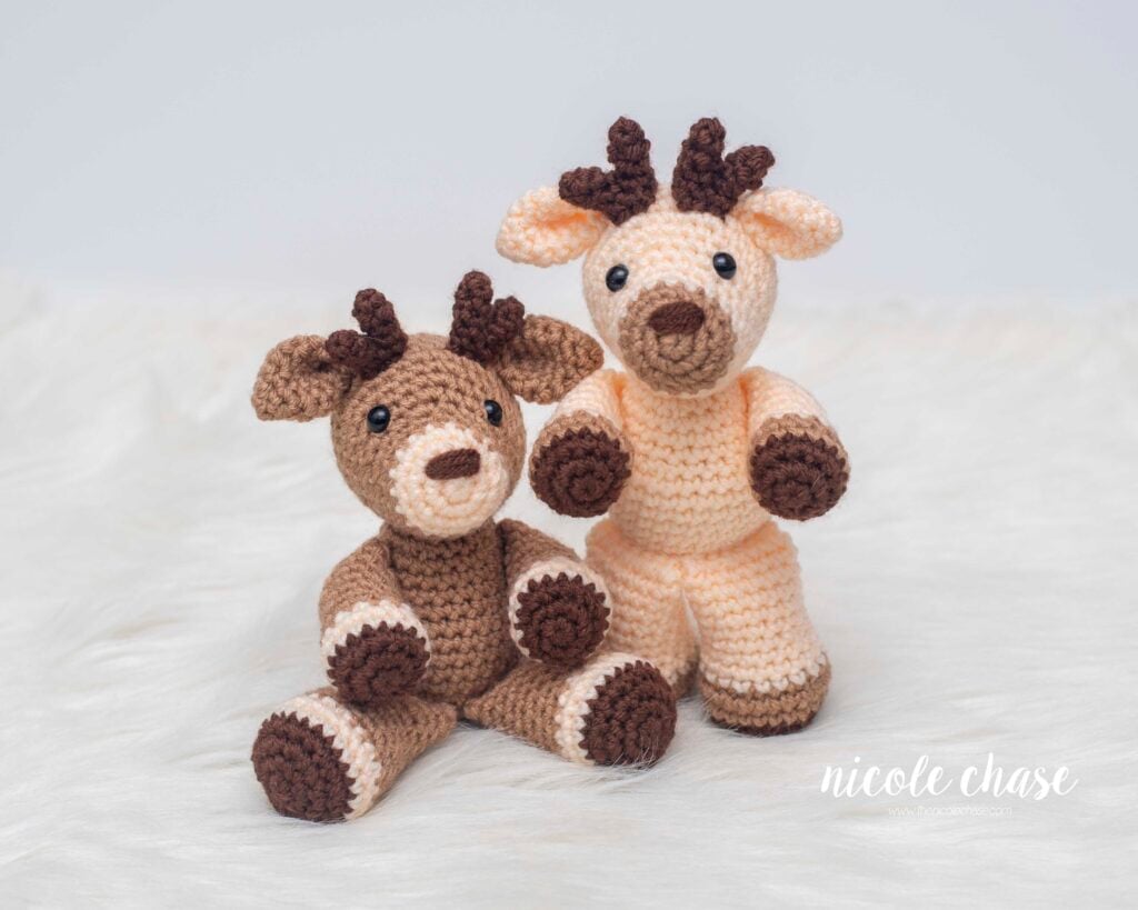 Two finished Randall amigurumi plushies made with this free deer crochet pattern (one in a light brown yarn and one in a cream colored yarn).