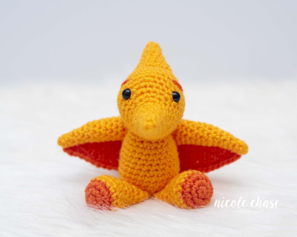 free pterodactyl crochet pattern shown in orange and yellow colors