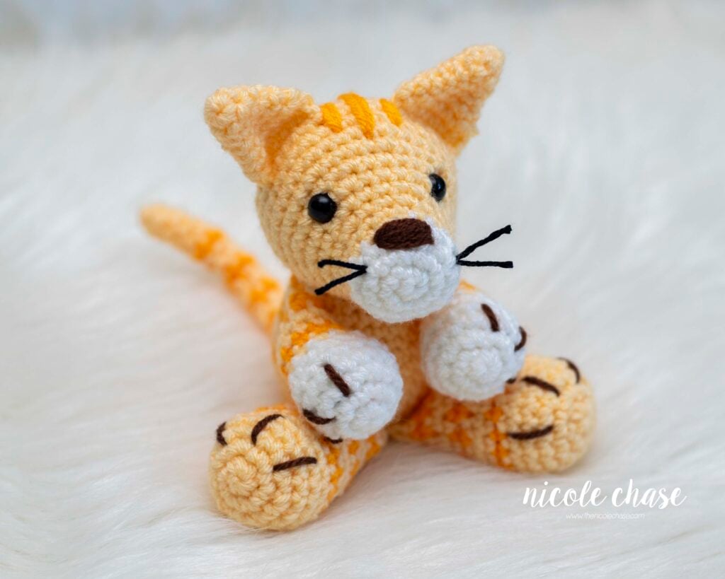 A small yellow and white amigurumi tabby cat named Cooper, a free cat crochet pattern. 