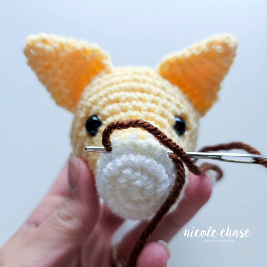 Embroidering the nose on the cat crochet pattern, step 2.