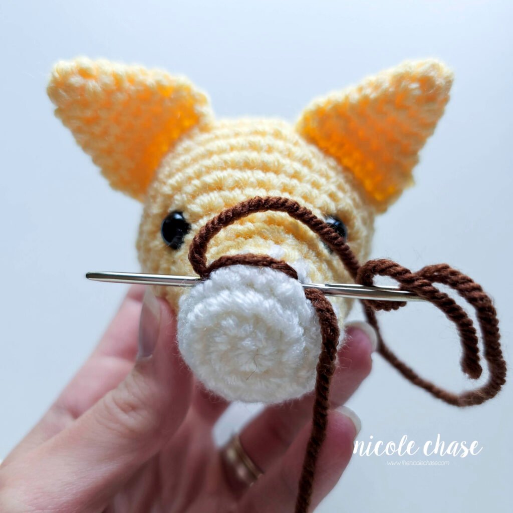 Embroidering the nose on the cat crochet pattern, step 3.